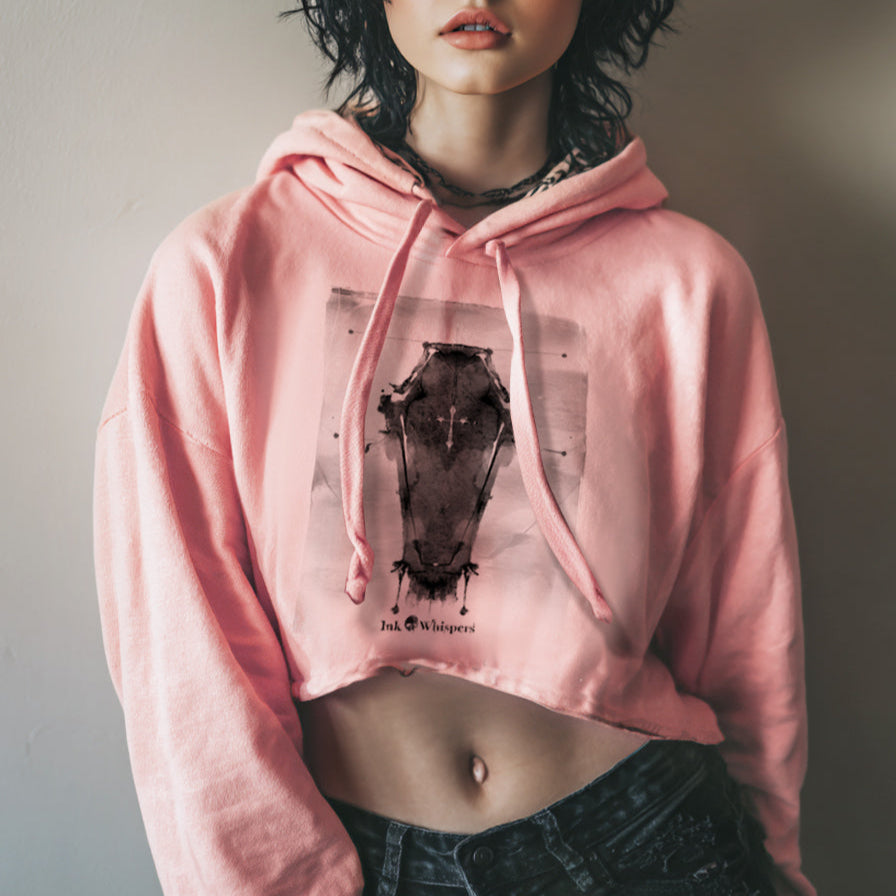 Person wearing a pink hoodie with a graphic design, standing against a plain background
