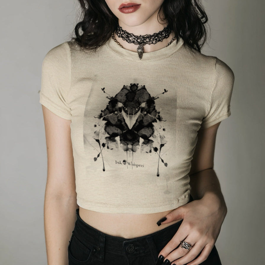 Woman wearing a beige t-shirt with a black graphic design on a plain background