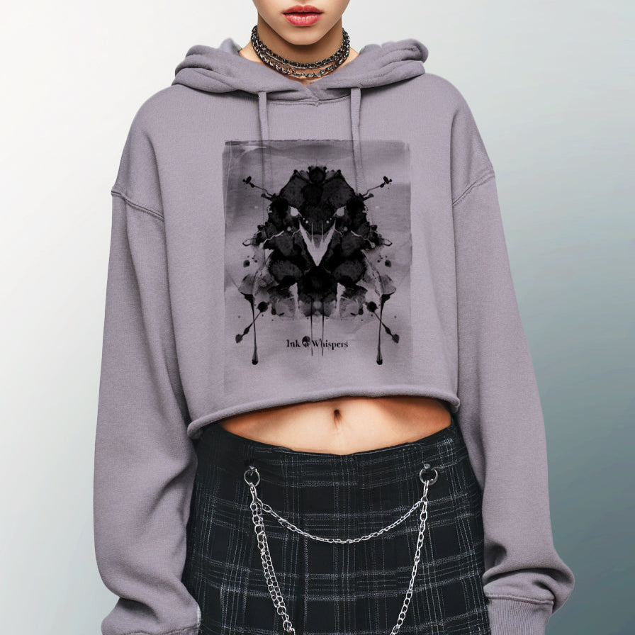 Person wearing a gray hoodie with a black graphic design and a plaid skirt with chains on a light gray background