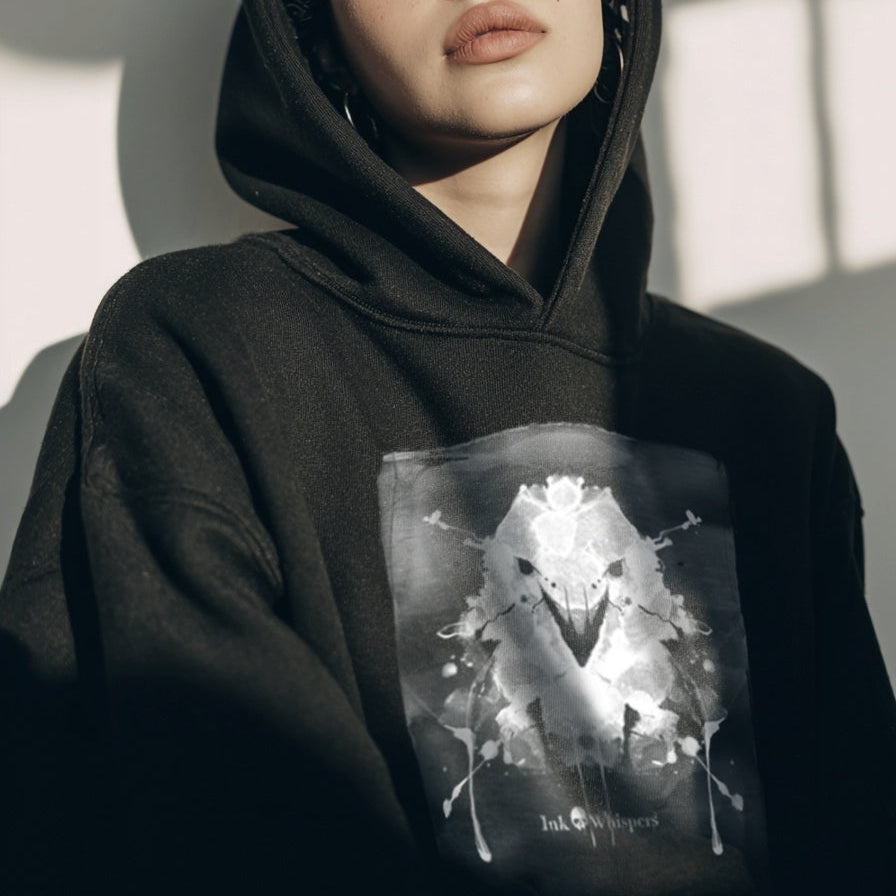Person wearing a black hoodie with a graphic design, sitting against a neutral background.
