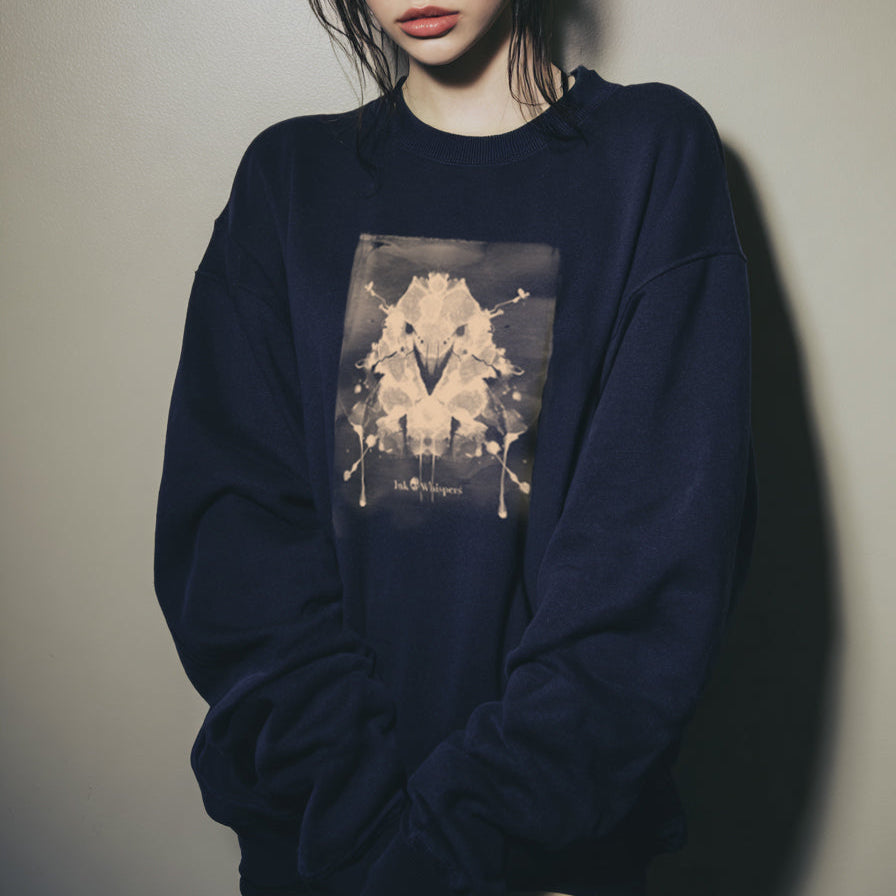 Person wearing a navy blue sweatshirt with a graphic design on a plain background