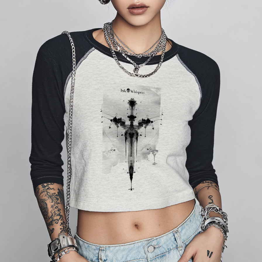 Person wearing a black and white long-sleeve shirt with a graphic design, denim shorts, and multiple necklaces and bracelets on a gray background.