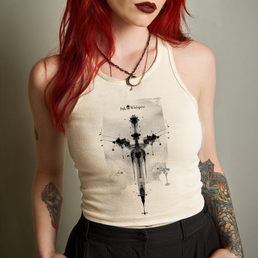 Woman with red hair and tattoos wearing a tank top with a graphic design.