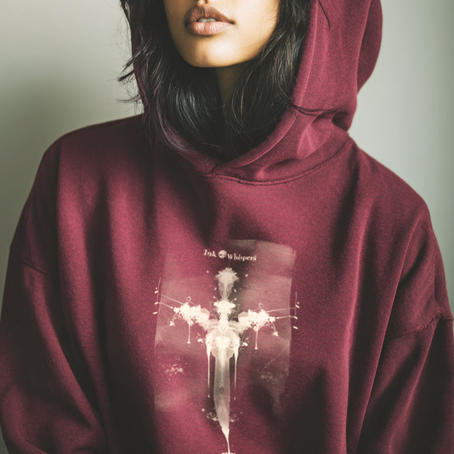 Person wearing a maroon hoodie with a graphic design on a plain background