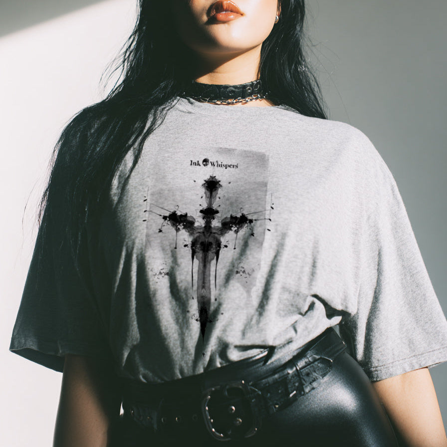 Person wearing a gray t-shirt with a graphic design, standing against a neutral background