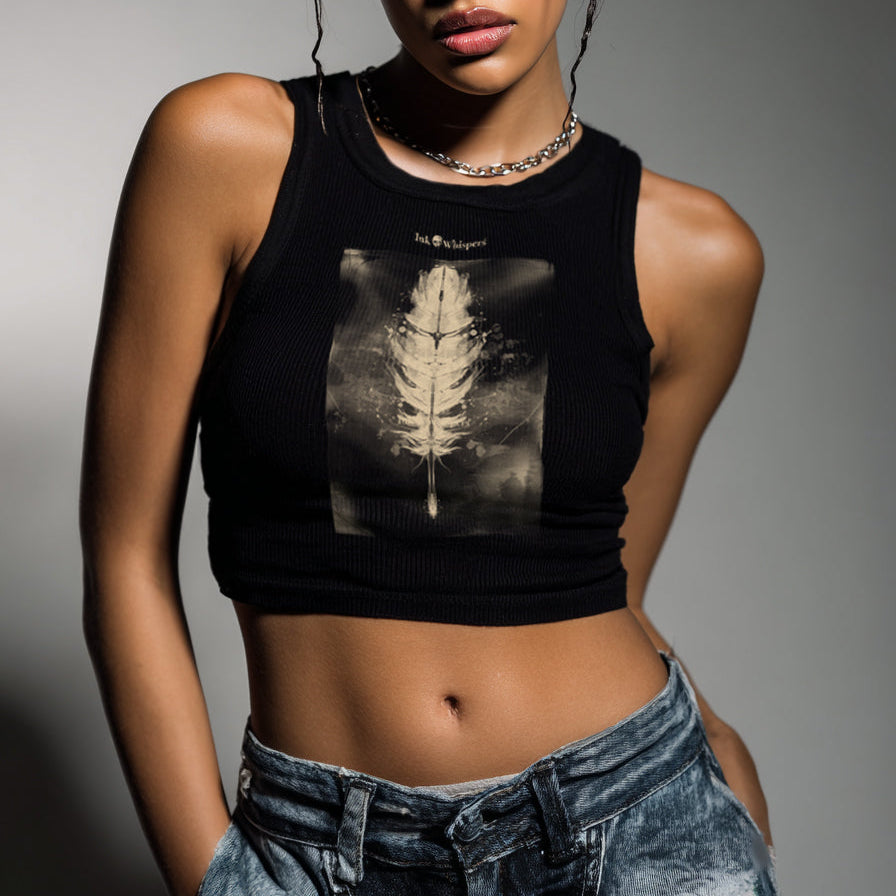 Person wearing a black sleeveless top with a leaf design and ripped jeans against a gray background