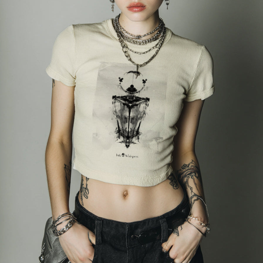 Person wearing a beige t-shirt with a graphic design, standing against a plain background