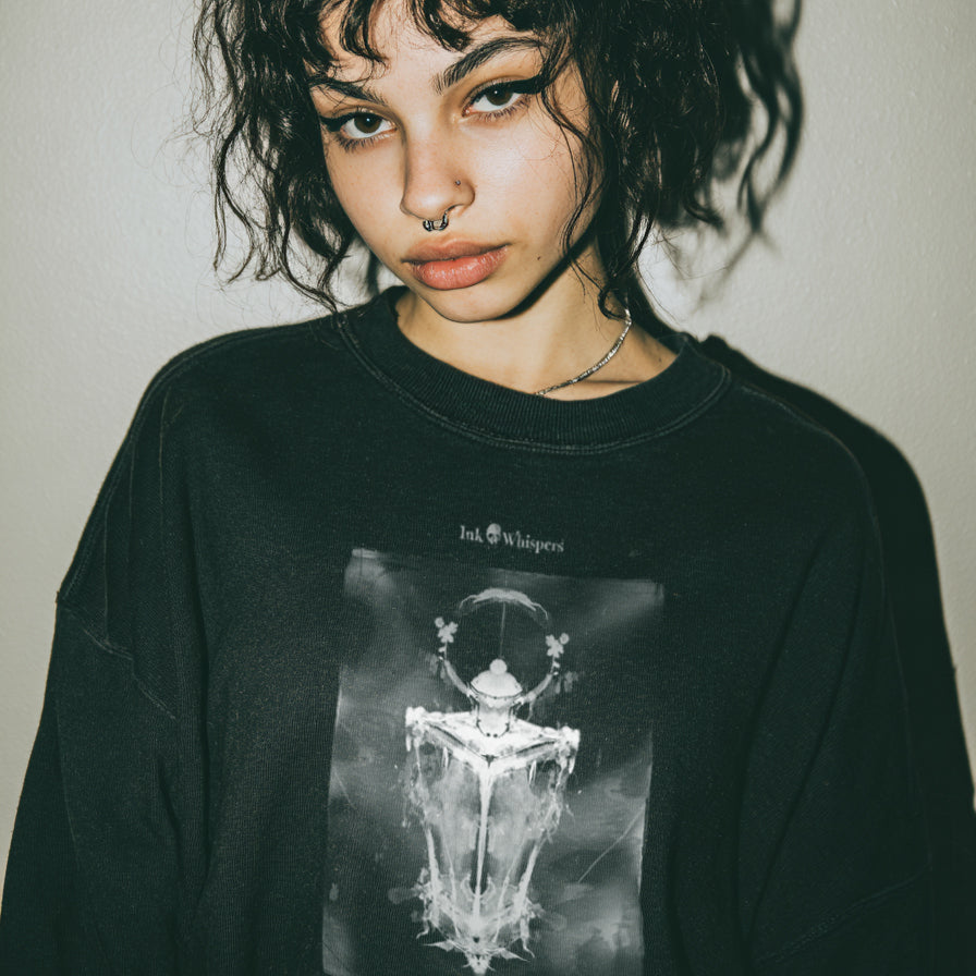 Person wearing a black sweatshirt with a graphic design on a plain background