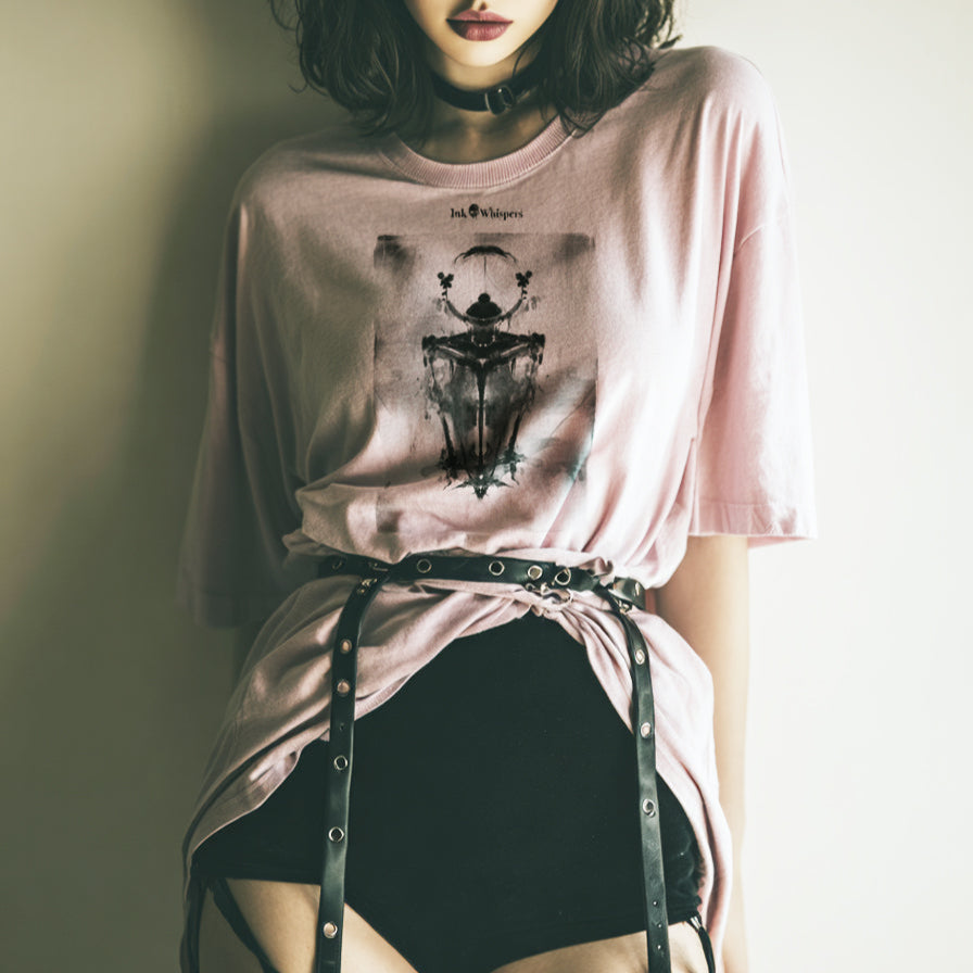 Woman wearing a pink t-shirt with a graphic design, sitting against a plain background.
