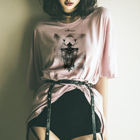 Woman wearing a pink t-shirt with a graphic design, sitting against a plain background.